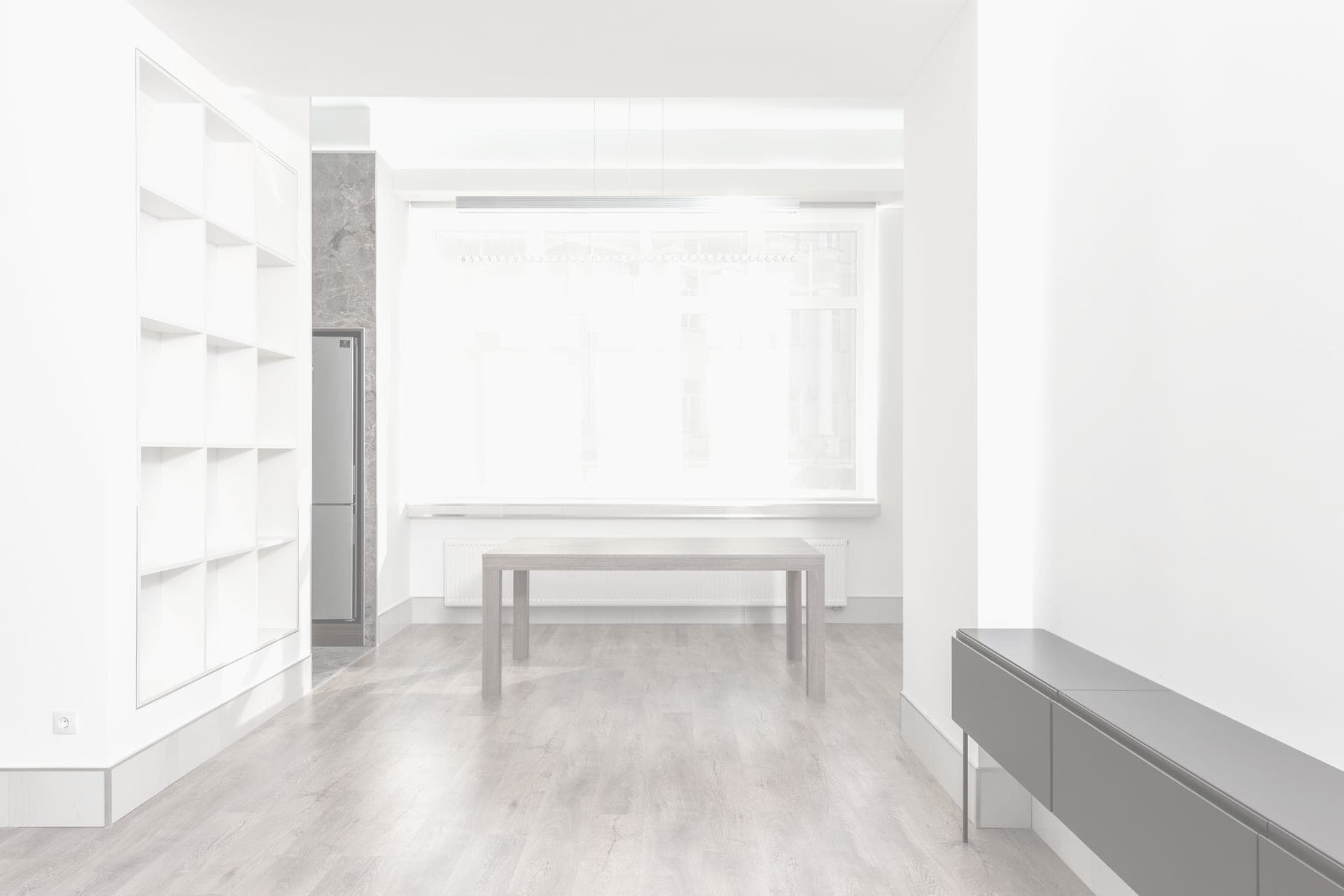 A sunlit empty room with pale wooden flooring