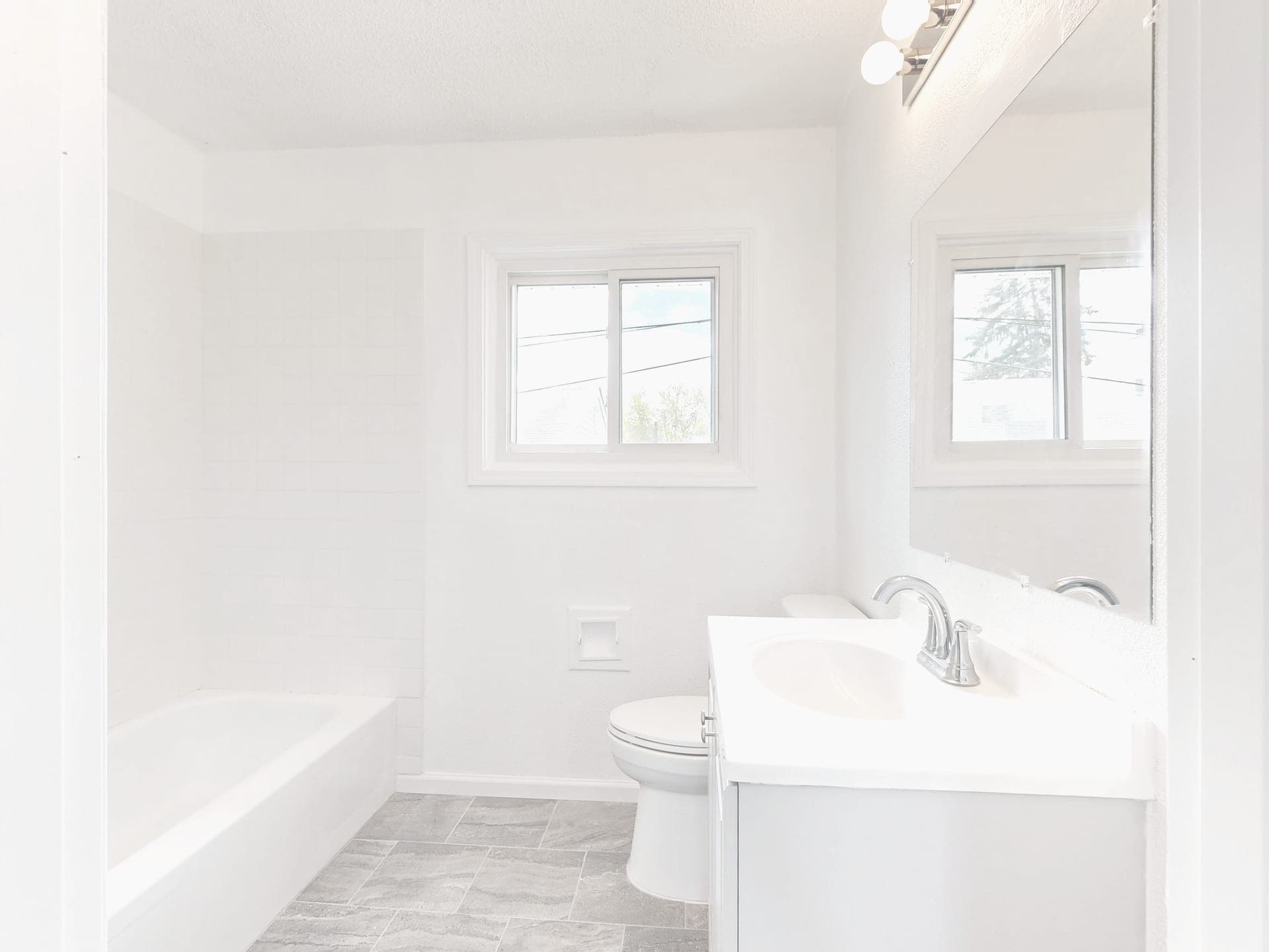 A bright bathroom with white tile flooring lit by natural daylight